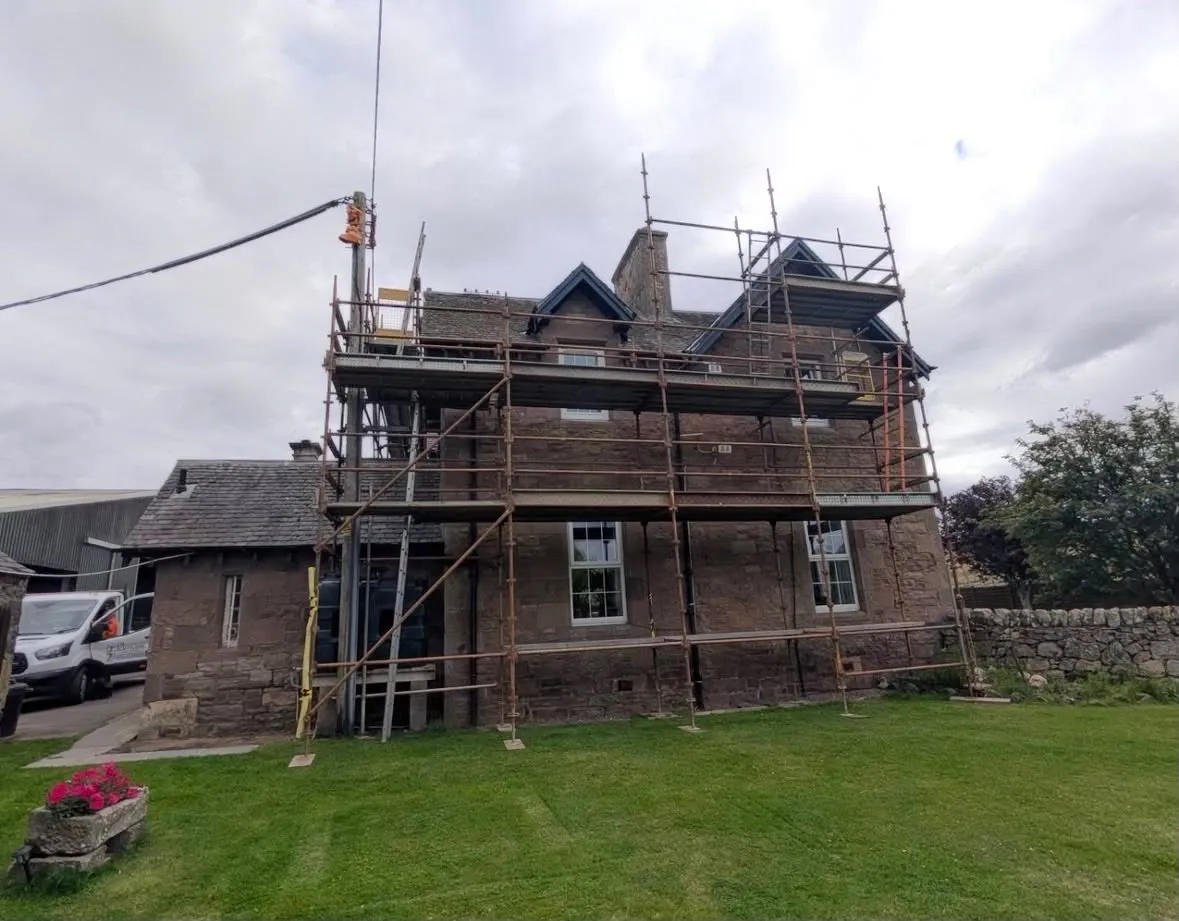 Scaffolding around a two-storey stone house